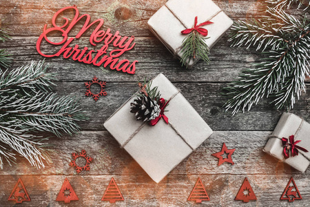 木制方形背景。红色欢快的圣诞铭文, 文字空间, 冷杉树枝和礼物。顶部视图。具有光效的冬季元素