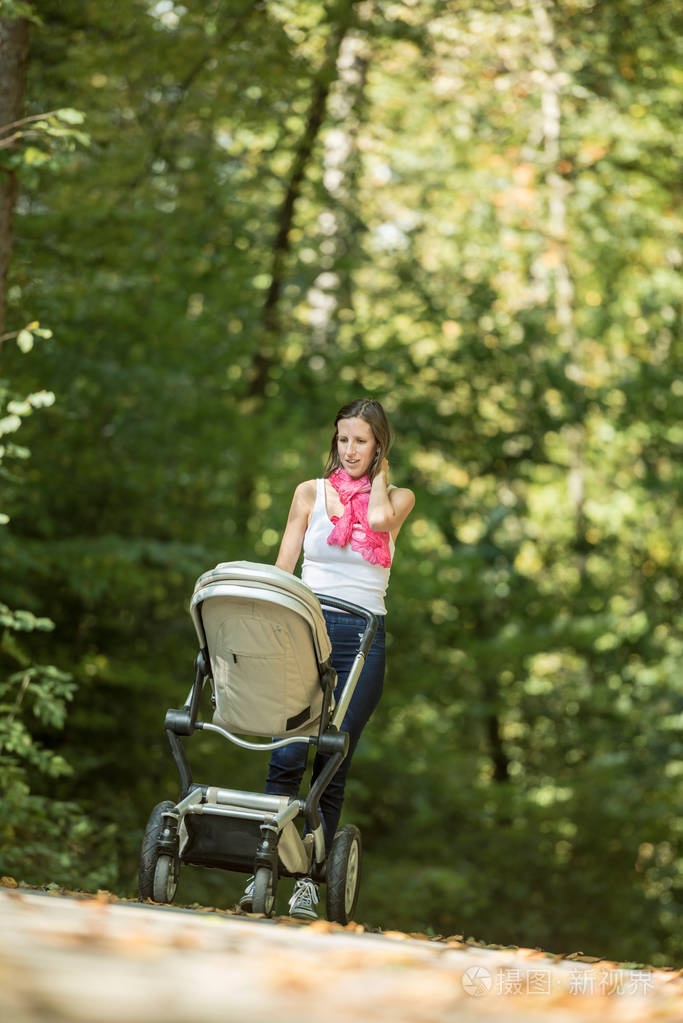 母亲推着一辆婴儿车或婴儿马车沿着乡间小路竹竿