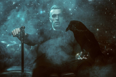 一个带着拐杖的吸血鬼男人坐在沙发上抱着一只黑乌鸦.