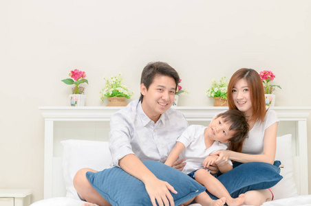 亚洲快乐家庭在卧室的白色床上, 爱和关心的概念