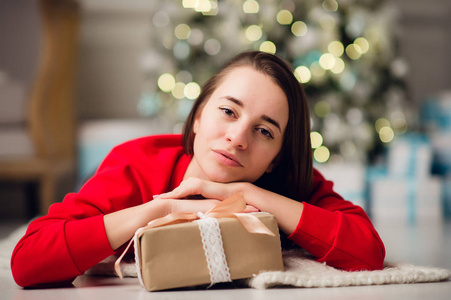 美丽快乐的年轻女子躺在地上抱着一份圣诞礼物