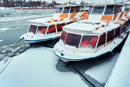 四艘游船在冬季的雪地和冰上站在码头上