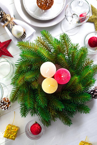 圣诞花圈与五颜六色的大蜡烛在桌子上, 在一个白色的木桌上的圣诞餐桌设置, 顶部视图