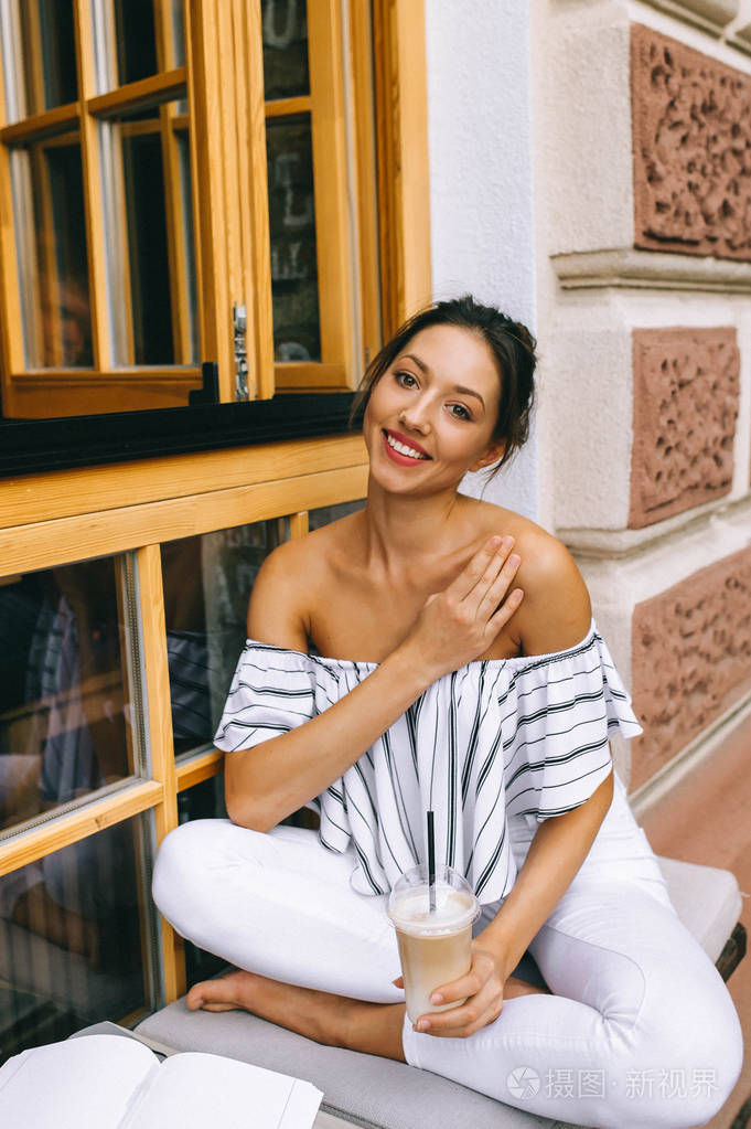 在城市喝咖啡的美丽的年轻妇女