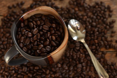 在陶瓷咖啡杯中特写新鲜烘焙咖啡豆的图片