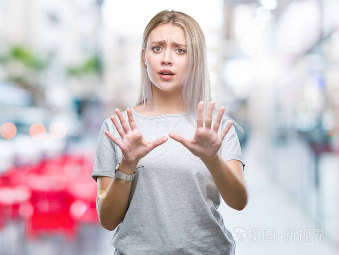 年轻的金发女人在孤立的背景下害怕和恐惧的表情用手停止手势, 在震惊