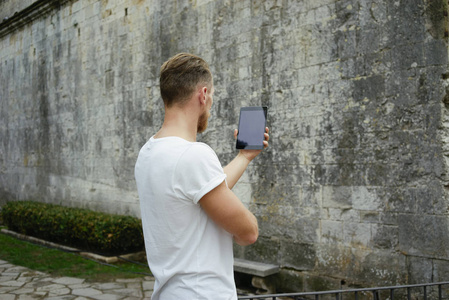 英俊的年轻人使用数字平板砖墙背景