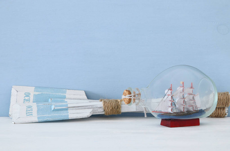 航海概念与木桨和小船在玻璃瓶在蓝色背景下