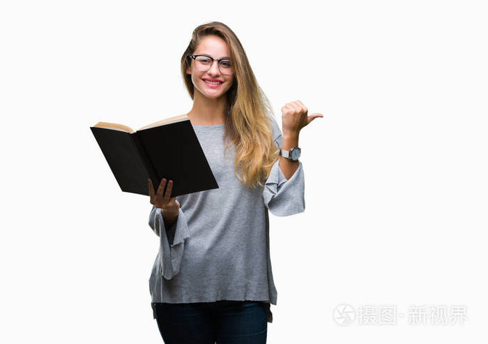 年轻美丽的金发碧眼的女人读一本书在孤立的背景指向和显示与快乐的脸微笑的一侧