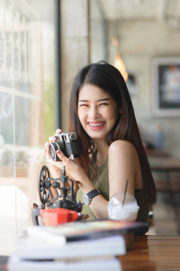 愉快的亚洲妇女藏品古董照相机在咖啡馆, 生活方式具体
