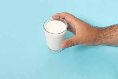 在蓝色背景的手抓杯牛奶