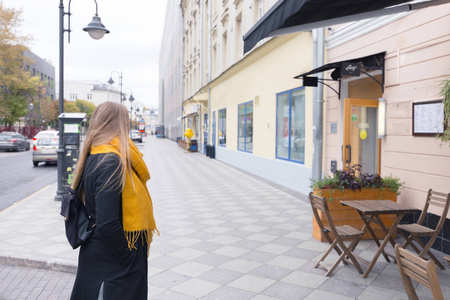 德国旅游女孩在旧莫斯科的历史中心。一个长头发的金发女子在大衣和黄色围巾