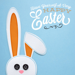 一只兔子在蓝色背景上的纸制成的创意复活节概念照片