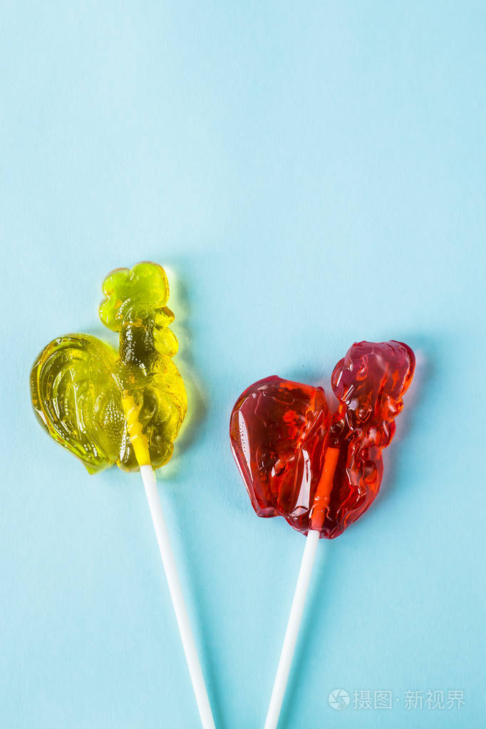 红色和黄色的糖果形状的公鸡复古糖果在蓝色背景上顶部视图平躺