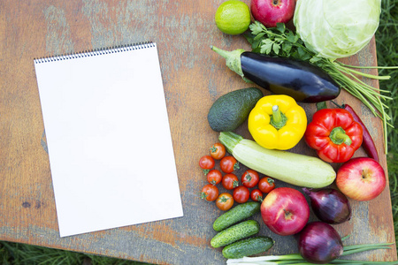 在乡土木桌和笔记本上设置新鲜的有机蔬菜和水果。节食计划。健康食品。顶部视图。从上面