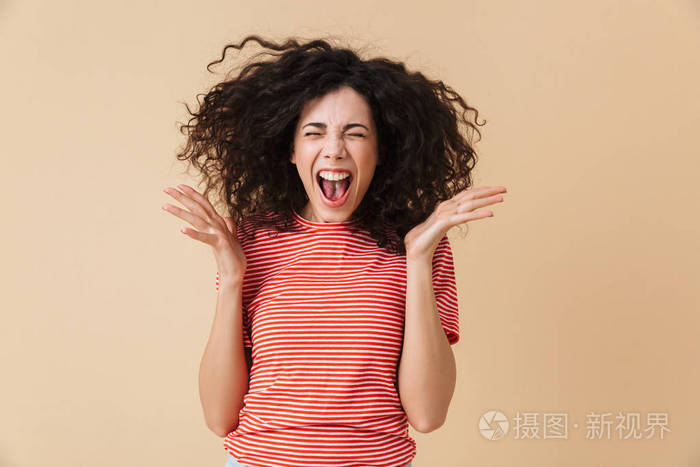 在米色墙壁背景被隔绝的激动尖叫的年轻妇女的相片照片-正版商用图片