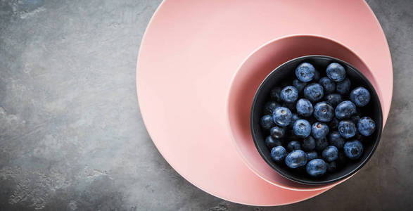新鲜蓝莓在粉红色的碗在黑暗的具体背景