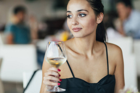 美丽的女人坐在餐厅品尝葡萄酒