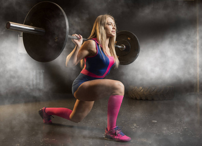 一个肌肉发达的女人在健身房锻炼与杠铃的肖像。Crossfit 风格