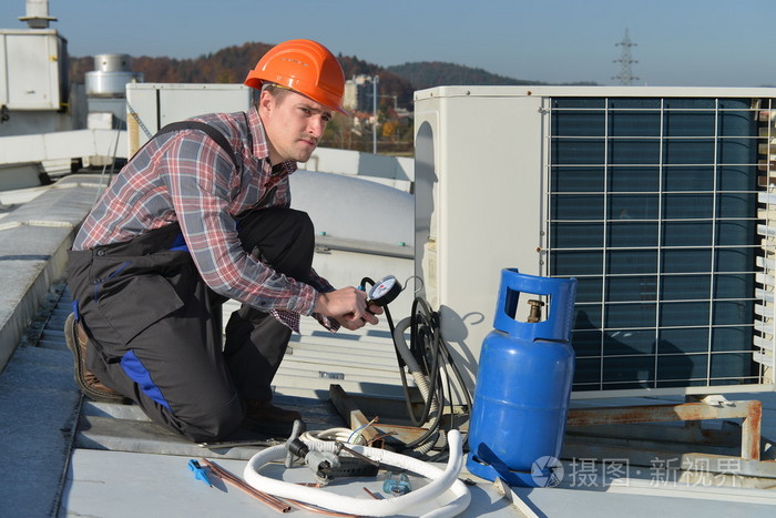 年轻修理工修理空调系统的屋顶上