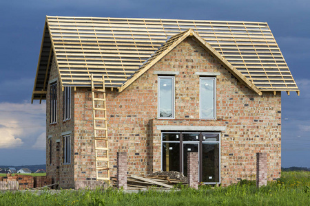 高木梯子在砖墙和砖专栏为篱芭在深蓝天空背景照片