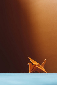 橙色折纸鸟, 用纸折纸的鸟。软焦, 浅色织物靠垫