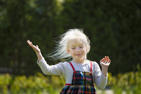 在草地上跳着白发的小女孩。在风中飘扬的头发。理念 快乐, 快乐童年