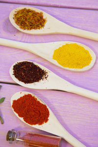 烹饪热辣食品的概念。干香料, 豆类和草药在玻璃瓶与软木和木匙, 紫色木制的背景, 顶部视图