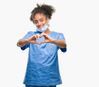 年轻的美国黑人医生在孤独的背景微笑的爱显示心脏符号和形状与手。浪漫理念