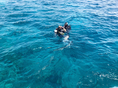 两名潜水员在黑色潜水防水西装与闪亮的金属铝罐漂浮, 沉浸在蓝色的海水度假, 巡航