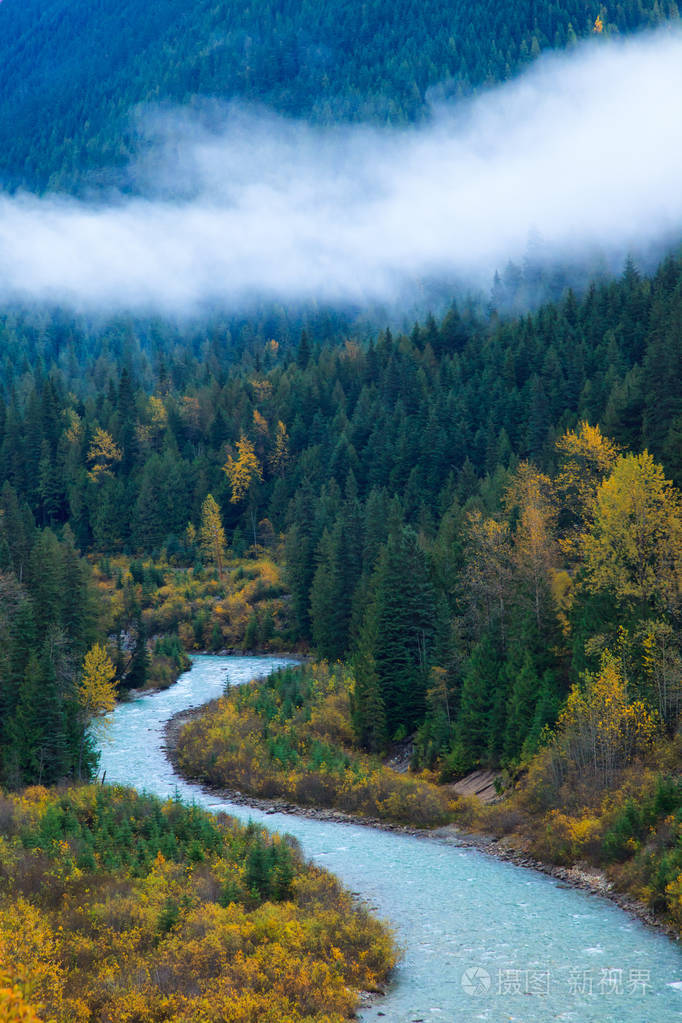 一条群山环绕着五颜六色的秋树和低云