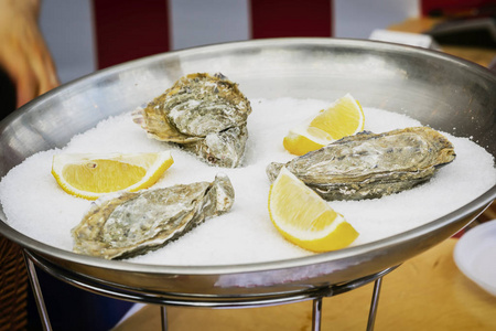 新鲜的牡蛎在金属板材与冰和柠檬特写。美食美品市场专柜 , 食品市场真实场景
