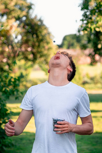 男孩享受新鲜的蓝莓户外站在花园里的夏天。穿白色 t恤衫的年轻男孩