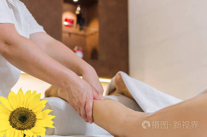 设备专业按摩师在水疗美容沙龙接受腿部推拿的女子