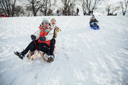 小女孩在下雪的时候在山上玩雪橇赛跑。