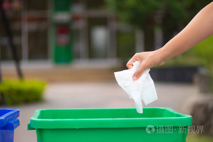 世界环境日6月5日妇女手捧和把纸巾废料放进垃圾桶里