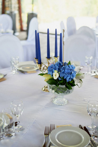 表与经典设计。在一个高花瓶与绣球和百合的组合, 一个金色烛台与蓝色蜡烛。装饰和植物
