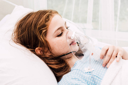 可爱的小女孩在她的脸上的氧气面罩在医院的床上照片