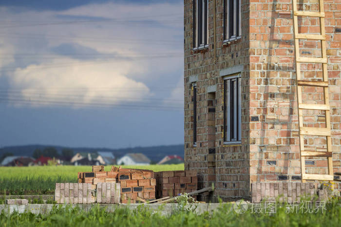 两层楼的房子里有塑料窗户和门开着的建筑在红砖墙和砖堆的高木梯房