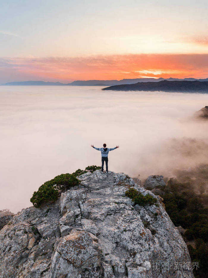 一个人站在悬崖边上上面覆盖着海的浓雾在克里米亚的kosmos山上
