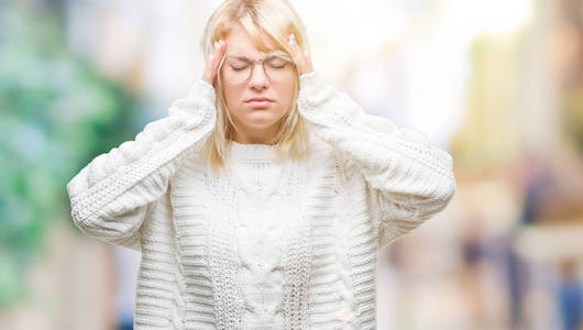 年轻美丽的金发女子穿着冬季毛衣和眼镜在孤立的背景与手头部疼痛头部因为压力。患偏头痛