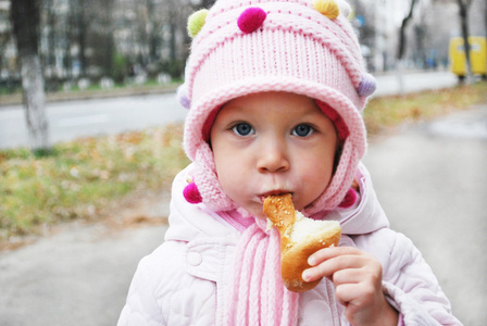 在街上一个小女孩在吃一块面包