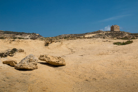 干燥的岩石和沙地国家与一个历史圣保罗塔在戈佐岛, 马耳他。蓝天