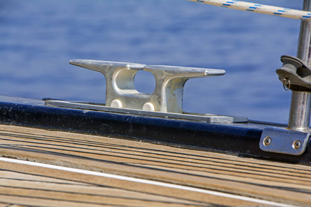 在模糊前景下, 用木质甲板将游艇停泊在船上的钢丝桩。选择性聚焦