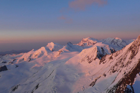 在一个寒冷美丽的冬日早晨, 在瓦莱州瑞士阿尔卑斯山的萨斯费上方的米沙贝尔山脉上, 日出和黎明