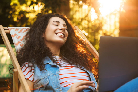 快乐情绪的形象年轻漂亮的女人在公园户外休息使用笔记本电脑