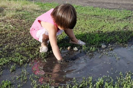 夏天小女孩在水坑里玩耍.雨后黑泥水坑.探索环境世界照片