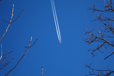 床身长长的拖尾的喷气式飞机在蔚蓝的天空照片