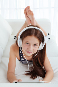 漂亮的小女孩在房间里的沙发上听音乐