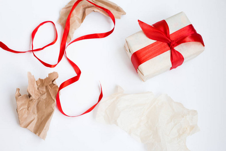 礼品包装过程。未成功尝试打包框。包装的礼物与丝带和包装纸的碎片周围白色背景。选择性聚焦